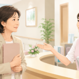 40代・50代の女性が医療機関の受付で医療事務スタッフと笑顔で相談している様子
